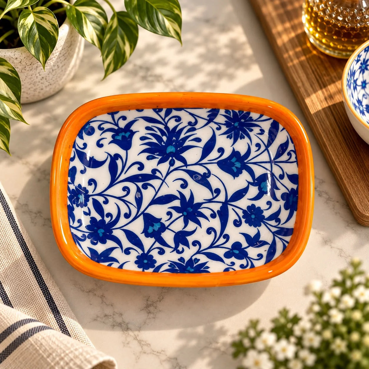Plato rectangular de cerámica con borde naranja, flores azules densas sobre fondo blanco