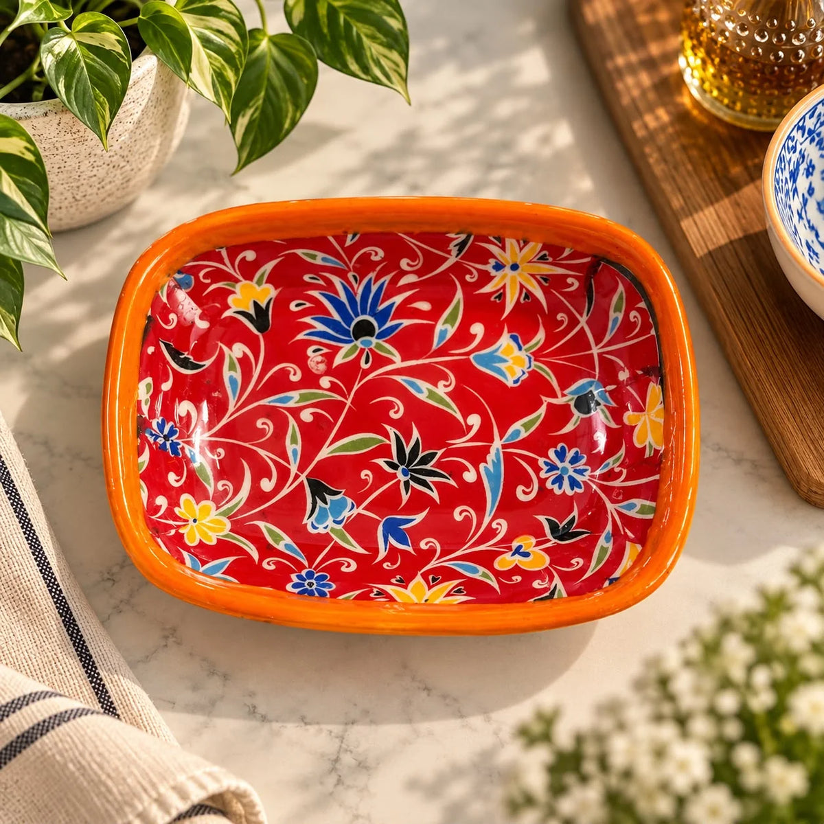Bandeja con flores azules y amarillas tipo estrella sobre fondo rojo y borde naranja