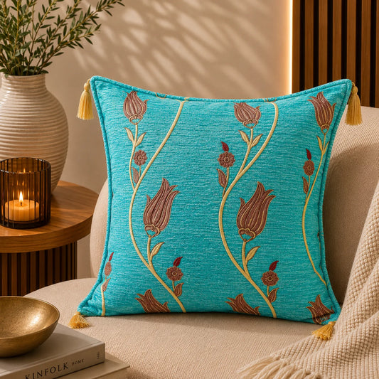 Almohadón turco con tulipanes en terracota sobre tallos dorados serpenteantes, en fondo turquesa, con borlas