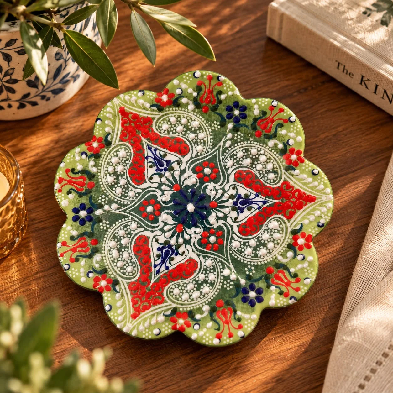 Apoya fuente de forma floral en verde con motivos paisley rojos, flores azul marino y puntos blancos
