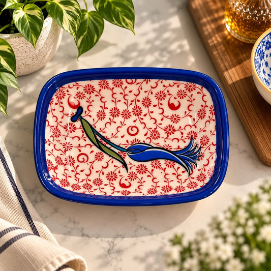 Plato de cerámica con borde azul, fondo de flores rojas y tulipán central azul verdoso