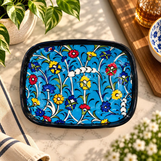 Plato rectangular de cerámica con borde negro y flores multicolor sobre fondo turquesa
