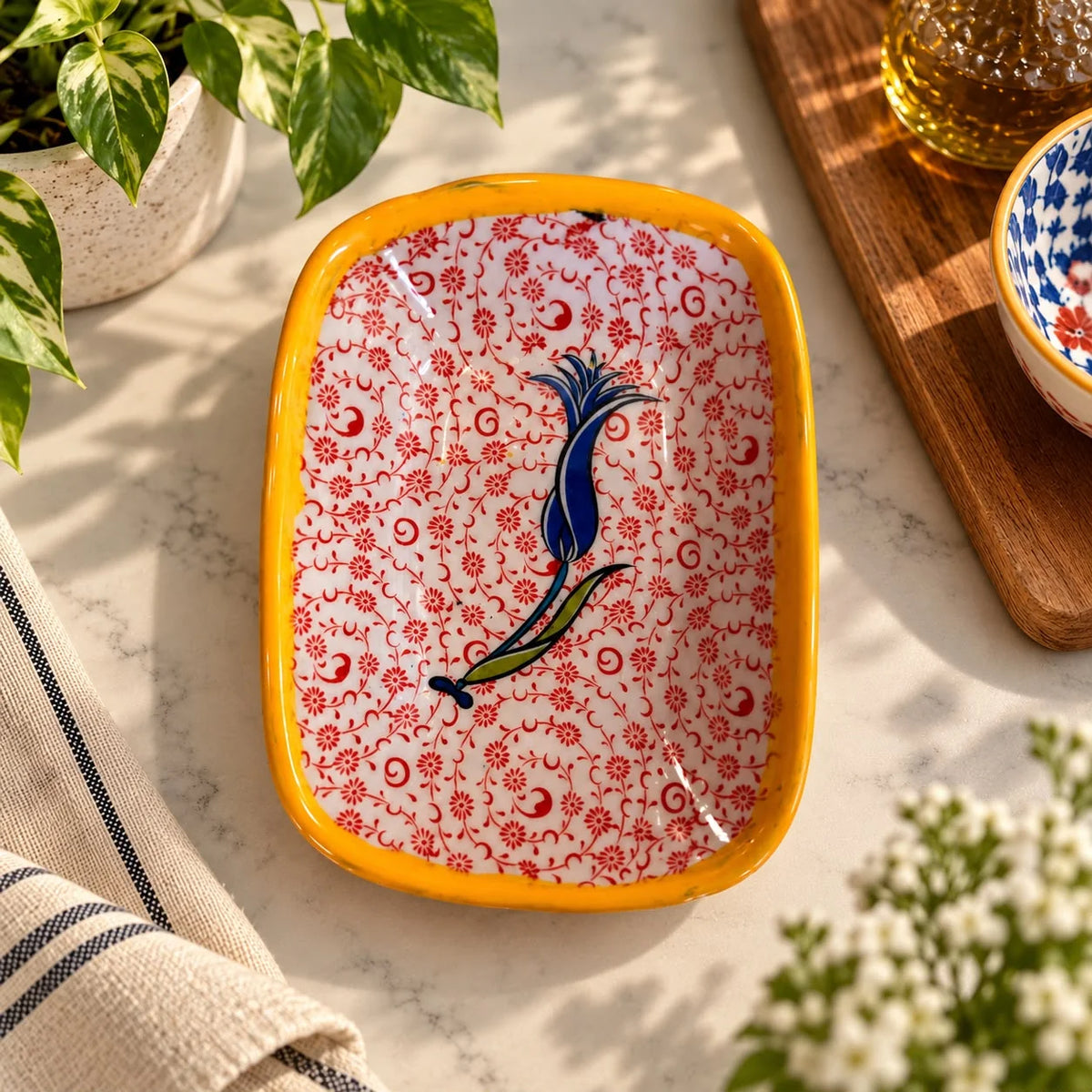 Bandeja blanca con estampado floral rojo fino y un tulipán azul central, borde amarillo mostaza