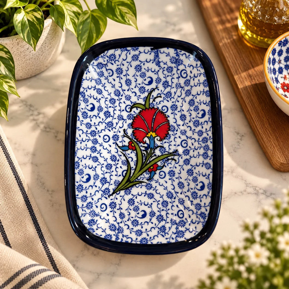 Bandeja blanca con estampado floral azul fino y un clavel rojo central, borde azul marino