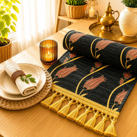 Camino de mesa negro con tulipanes coral perfilados en dorado y pequeñas flores rojas, bordado en relieve, con flecos de borlas doradas.