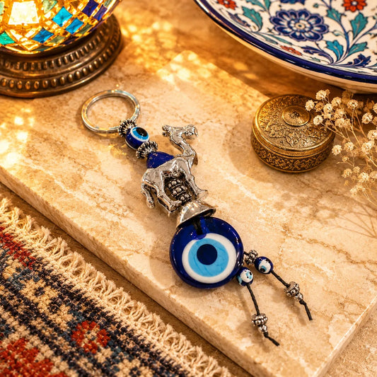 Llavero Camello Plateado: Camello metálico plateado con piedra azul y colgante de ojo turco.