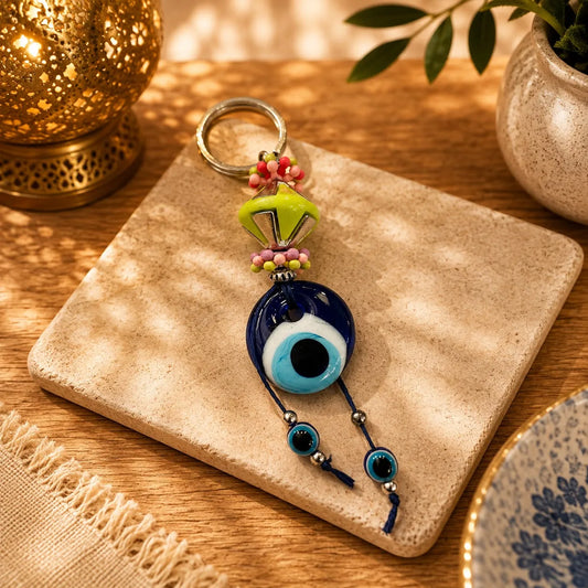 Llavero Ojo Turco Rosa y Verde: Ojo turco azul junto a una flor verde lima, con cuentas rosa y verde alrededor.